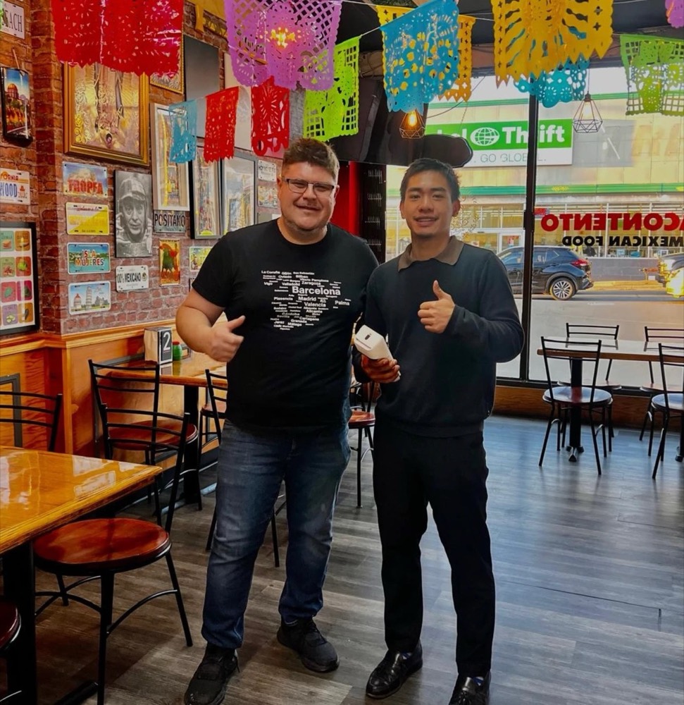 GT Payments rep and a Mexican restaurant owner giving a thumbs up in the dining room, holding a Clover terminal